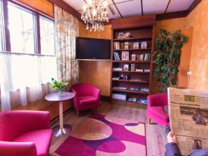 a living room with pink chairs and a tv at Kauppahotelli in Lahti