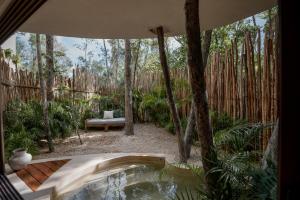 a hot tub in the middle of a garden with trees at Rubi Tulum in Tulum