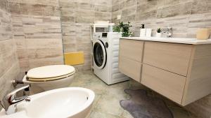 een badkamer met een wasmachine, een toilet en een wastafel bij Welcomely - Via Gramsci 31 WiFi vista collina in Bosa