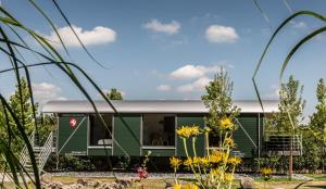 a green caravan with a grey roof in a garden at LokoMotel-Waggon, Luxus Appartment im Eisenbahnwaggon in Stadtlohn