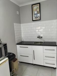 uma cozinha com um lavatório e um micro-ondas em The Terrace Guest House em Roodepoort