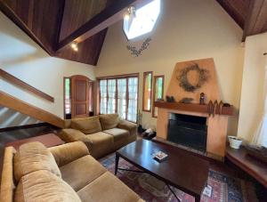 a living room with a couch and a fireplace at Villa di Caserta by Capivari Lodge Home in Campos do Jordão