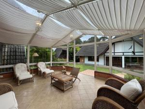 a patio with awning and chairs and a table at Villa di Caserta by Capivari Lodge Home in Campos do Jordão
