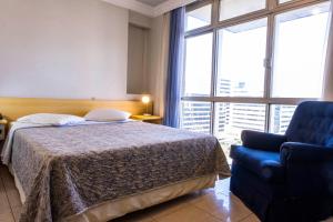 um quarto com uma cama e uma cadeira azul em Like U Hotel Brasília em Brasília