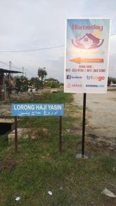 dos letreros sentados en el césped junto a una carretera en Homestay Embah Ros & Embah Lek, en Hutan Melintang