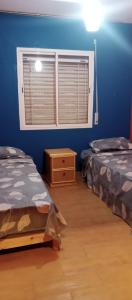 2 Betten in einem Zimmer mit blauen Wänden und einem Fenster in der Unterkunft dalas in Saidia 