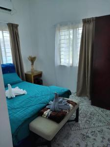 1 dormitorio con cama con sábanas azules y silla en Homestay Embah Ros & Embah Lek, en Hutan Melintang