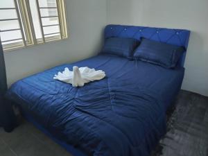 Una cama azul con una toalla encima. en Homestay Embah Ros & Embah Lek, en Hutan Melintang