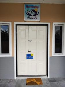 una puerta de garaje blanca con un cartel en ella en Homestay Embah Ros & Embah Lek, en Hutan Melintang
