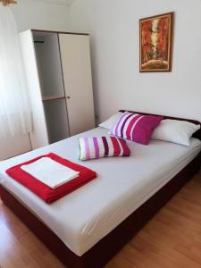 een wit bed met rode en paarse kussens erop bij Apartments Jele II in Sveti Petar