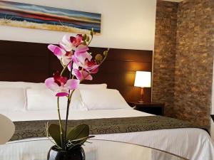 um quarto de hotel com uma cama com um vaso com flores em Europa Hotel Boutique Manizales em Manizales