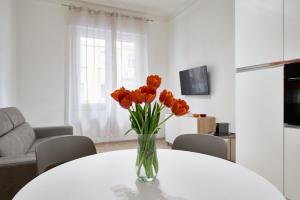 un jarrón de tulipanes naranjas sentado en una mesa en Casa Flaminia, en Roma