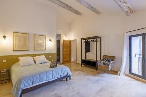a bedroom with a bed and a chair and a window at La Petite Maussanaise in Maussane-les-Alpilles
