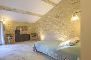 ein Schlafzimmer mit einem Bett und einer Steinmauer in der Unterkunft La Petite Maussanaise in Maussane-les-Alpilles