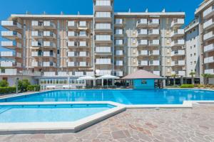 a swimming pool in front of a large apartment building at Residence Playa Grande Immobiliare Pacella in Lido di Jesolo