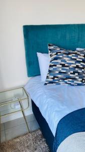 a bed with a blue headboard and a pillow on it at BALLITO HILLS, 1 bedroom apartment in Ballito