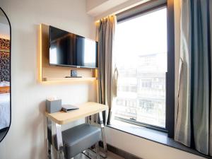 a room with a desk and a tv and a window at Belive&More in Macau