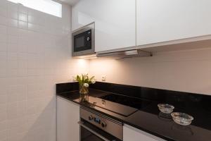 kuchnia z czarnym blatem i kuchenką mikrofalową w obiekcie Vivienda con zona de trabajo, piscina y parking w Madrycie