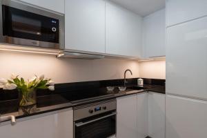 kuchnia z białymi szafkami i mikrofalówką w obiekcie Vivienda con zona de trabajo, piscina y parking w Madrycie +26 zdjęć