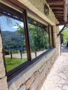 a window in a stone building with a view of a lake at Casa da Terra - Gerês in Geres