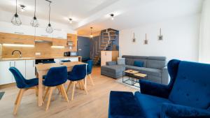 een keuken en een woonkamer met een tafel en blauwe stoelen bij Apartamenty EverySky - Dom Reymonta 9 in Karpacz