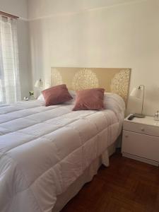 una camera da letto con un grande letto bianco con due cuscini di Arena a Mar del Plata