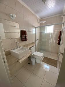 a white bathroom with a sink and a toilet at Aluga-se casa para Temporada in Águas de Lindóia