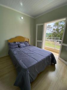 1 cama grande en un dormitorio con ventana grande en Aluga-se casa para Temporada en Águas de Lindóia