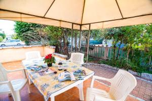 un tavolo con sedie bianche e un ombrellone di residence lu soli budoni affitti a Budoni