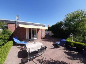 eine Terrasse mit Tisch und Stühlen und einem Sonnenschirm in der Unterkunft Ferienhaus Primavera in Dornumersiel