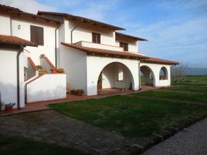 ein großes weißes Haus mit Bögen und einem Hof in der Unterkunft Azienda Il Tizzano in Albinia + 5 Fotos