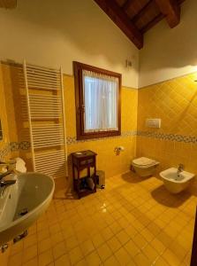 Baño de azulejos amarillos con lavabo y aseo en Bed and Breakfast Ca’ Pisani, en Stra