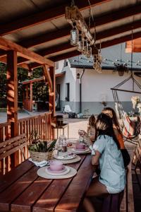 dos chicas sentadas en una mesa de madera con platos de comida en Domki RADAWA na Kliszówce, en Radawa