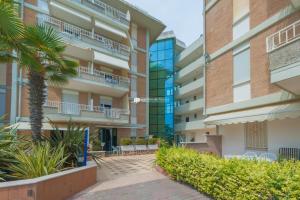 an apartment building with a palm tree in front of it at Residence Puerto Del Sol Immobiliare Pacella in Lido di Jesolo