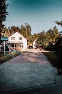 a driveway leading to a white building with a playground at Domki RADAWA na Kliszówce in Radawa