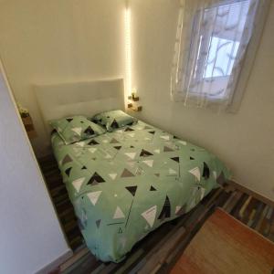 a bedroom with a bed with a green comforter at apt cosy, 4 pers, plein centre ville, parking offert in Font-Romeu-Odeillo-Via