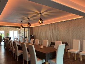 a dining room with a long table and white chairs at Öreg-tó Youth Hostel in Tata +13 photos