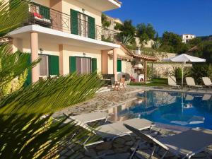 a villa with a swimming pool next to a house at PANTHEON RESORT AND VILLAS in Agios Nikitas