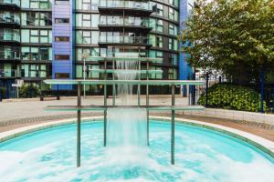une fontaine dans une piscine en face d'un bâtiment dans l'établissement Riverside Apartment, à Londres