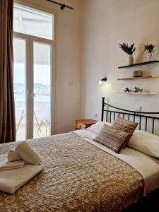 a bedroom with a bed and a large window at Casa di Syrii in Ermoupoli