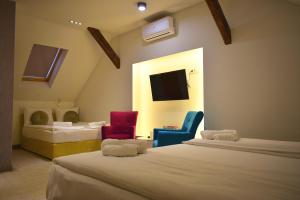 Pokój z dwoma łóżkami i dwoma krzesłami oraz telewizorem w obiekcie Deluxe Nortel Hotel w Sarajewie