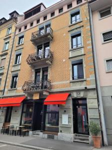 a brick building with red awnings on a street at HITrental Central Station Apartment in Zürich