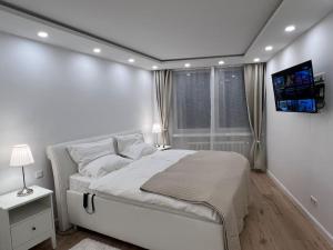 a white bedroom with a bed and a tv on the wall at Lovely HOME Suite in Nuremberg in Nürnberg