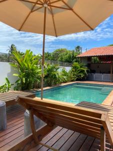 a wooden deck with an umbrella and a swimming pool at La belle de jour in Fortim