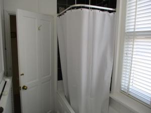 a bathroom with a white shower curtain next to a window at 3 Bed Flat - Sleeps 5 - Garden - Parking - Wifi in Ryde +7 photos