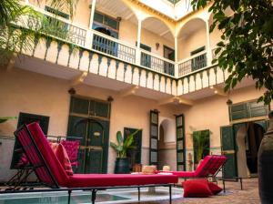 a patio with red chairs and a balcony at Riad Dar Habiba by Garden Wonders in Marrakesh