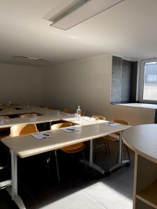 an empty classroom with tables and chairs and a window at MG-Quartier Hostel in Mönchengladbach