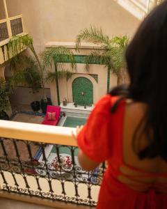 Eine Frau, die vom Balkon aus ein Modell eines Hauses anschaut. in der Unterkunft Riad Dar Habiba by Garden Wonders in Marrakesch