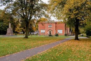 a brick building with trees in front of a park at Ansley house in Arley