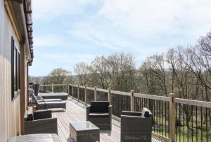 a deck with chairs and tables on a balcony at Fabulous detached lodge with hot tub two nights minimum stay in Bridgnorth